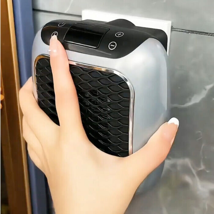 Hand steekt de WellHeater-stopcontactkachel rechtstreeks in een stopcontact in de muur